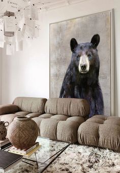 a living room filled with furniture and a large bear painting on the wall above it