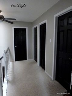 an empty hallway with black doors and white railing