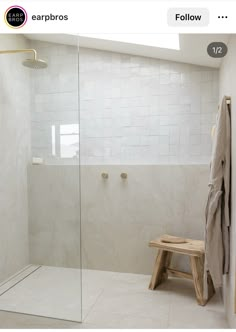 a walk in shower sitting next to a wooden bench under a skylight on top of a tiled floor