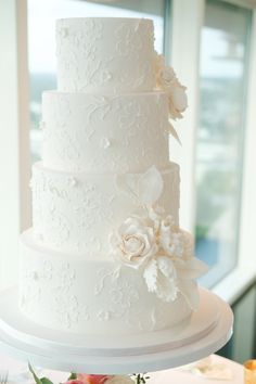 a three tiered white wedding cake with flowers