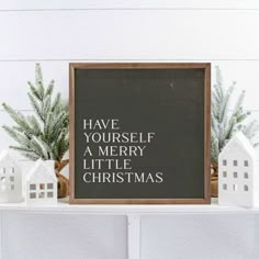 a chalkboard with the words have yourself a merry little christmas written on it next to small white houses