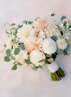 a bridal bouquet with white flowers and greenery