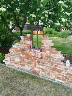 a cat sitting on top of a brick wall near a tree and flower potted planter