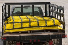 a bed in the back of a truck with a yellow blanket on it's flatbed