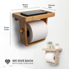 a wooden shelf with a phone on it next to a roll of toilet paper and a cell phone holder