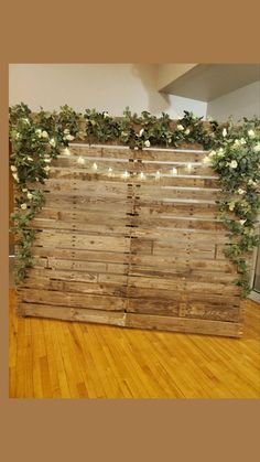 a wooden fence with vines and lights on it in the middle of a wood floor