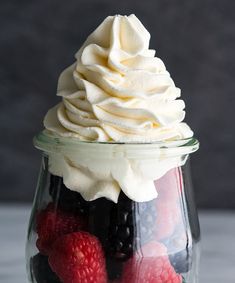 a glass jar filled with whipped cream and berries