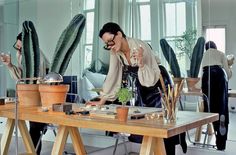 a man standing in front of a table filled with potted plants and succulents