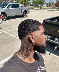 a man with tattoos on his neck standing next to a truck