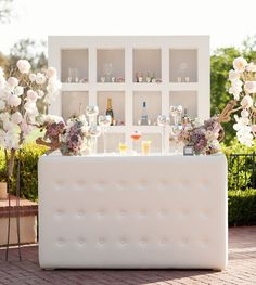 an outdoor bar with flowers and drinks on it