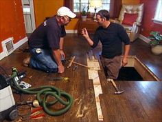 two men working on an unfinished floor in a house