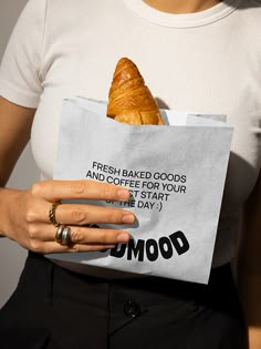 a woman holding a bag with a croissant in it's pocket and saying, fresh baked goods and coffee for our first start the day