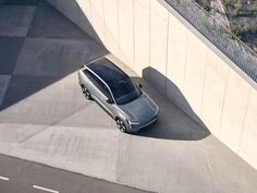 an aerial view of a silver car parked on the side of a road next to a wall