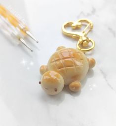 a tiny turtle keychain is sitting on a table next to some needles and scissors