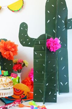 a cactus themed birthday party with cake, decorations and paper flowers on the table in front of it