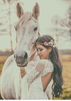 a woman standing next to a white horse