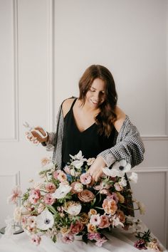 a woman standing in front of a table with flowers on it and holding a knife