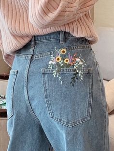 the back of a woman's jeans with flowers embroidered on it, in front of a white couch