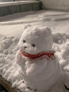 a snowman sitting in the middle of a pile of snow on top of a wooden pallet