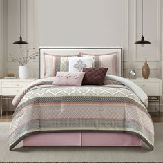 a bed in a bedroom with pink and gray comforter set on top of it