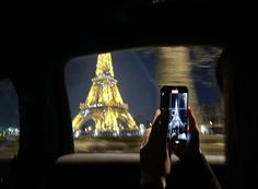 a person taking a photo in front of the eiffel tower at night