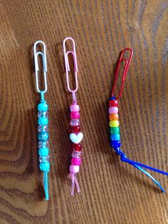 three different colored paper clips on top of a wooden table