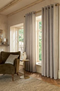 a living room filled with furniture and windows covered in gray drapes next to a fire place