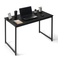 a laptop computer sitting on top of a black desk next to a cup and pen