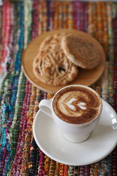 there is a cup of coffee and two cookies on the table