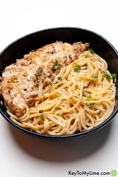 a black bowl filled with pasta and chicken