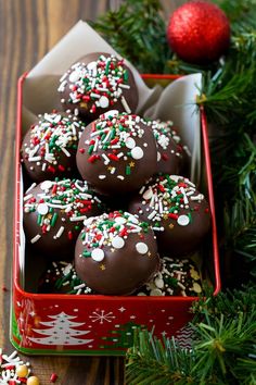 chocolate covered donuts with sprinkles and christmas decorations in a red box