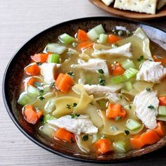 a bowl of chicken noodle soup with crackers on the side