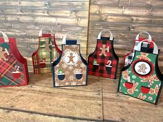 four christmas aprons are sitting on a table with wooden boards in the back ground