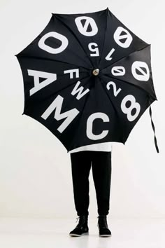 a person holding an open umbrella with letters on the front and sides, in black and white