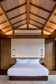 a large bed sitting under a wooden ceiling next to two lamps on either side of it