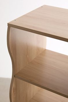 a wooden shelf sitting on top of a hard wood floor next to a white wall