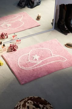 two pink rugs with hats on them in front of a bathroom mirror and other accessories