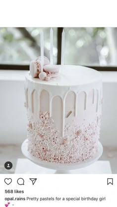 a white cake with pink frosting and sprinkles sitting on top of a table