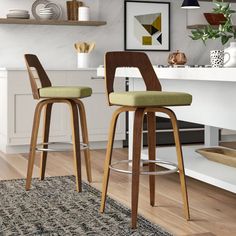 two wooden barstools with green upholstered seats sit in front of a kitchen counter