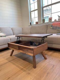 a coffee table with an open drawer underneath it in a living room next to a couch