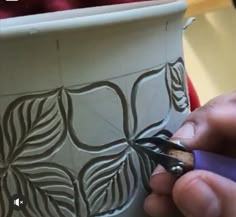 a person is using scissors to decorate a vase