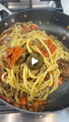 a pan filled with spaghetti and meat on top of a stove