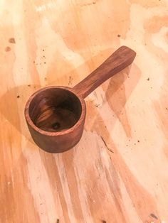 a wooden spoon sitting on top of a wooden table next to a knife blade in the shape of a bowl