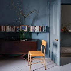 a wooden chair sitting in front of a blue wall with bookshelves on it