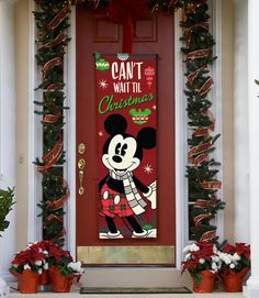 a mickey mouse christmas door hanger on a red front door with garland and potted plants