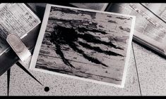 a black and white photo of an old wooden table with papers on it, next to a pair of scissors