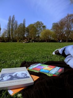 an open book sitting on top of a blanket in the grass next to a book