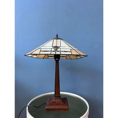 a stained glass lamp sitting on top of a round table next to a blue wall