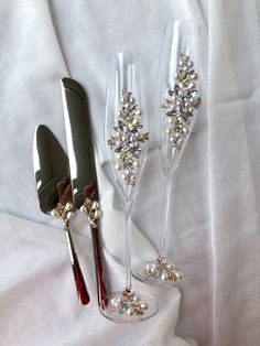 three wine glasses with silver and red decorations on them sitting next to a pair of scissors