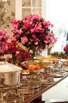 a buffet table filled with lots of different types of food and flowers in vases